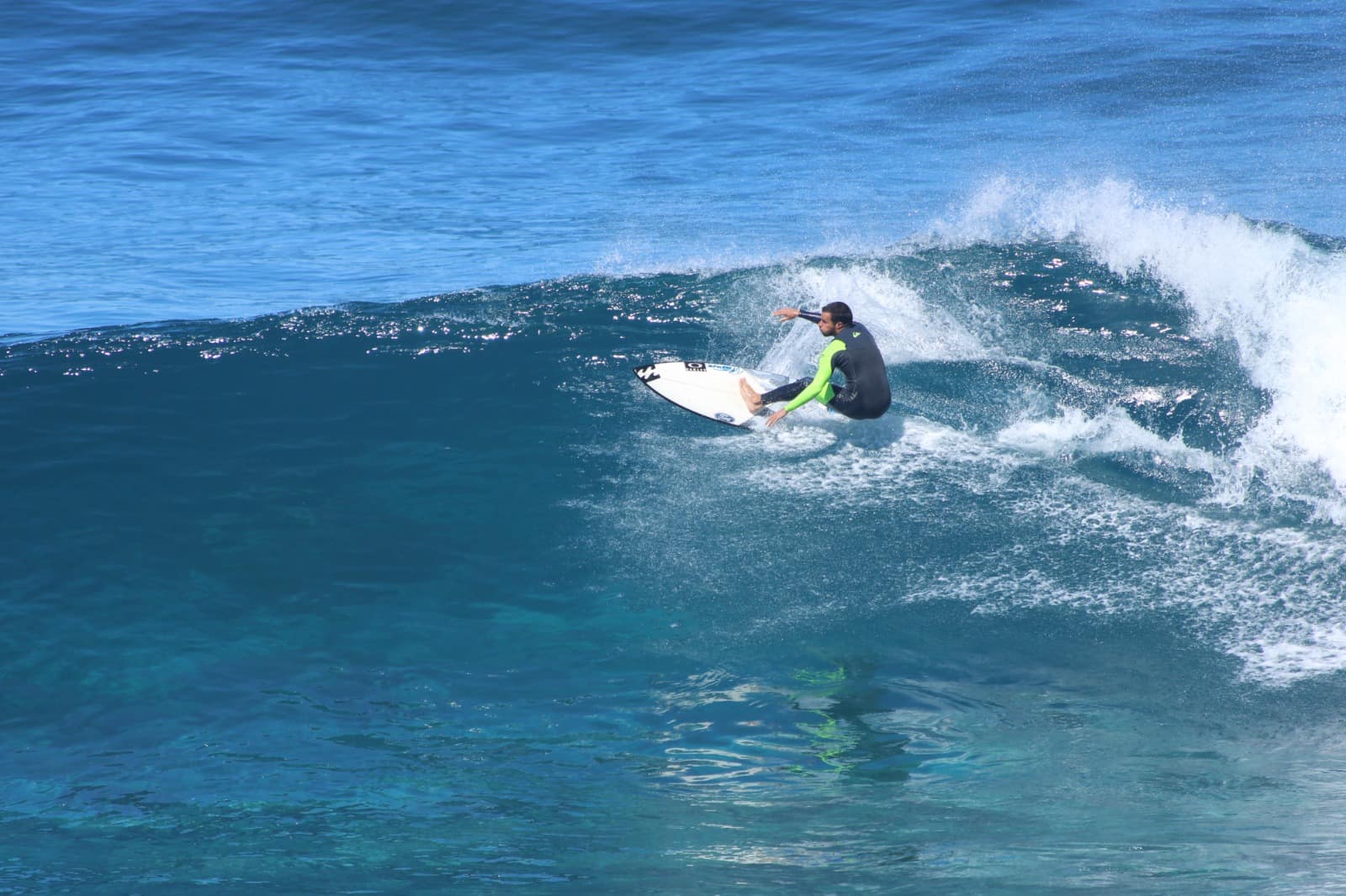 Surfista a fazer uma manobra numa onda de água azul.